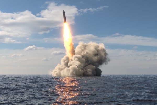 a rocket being launched from an ocean platform with a fiery tail and plumes of smoke